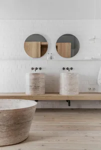 Modern bathroom with marble sinks and round mirrors.
