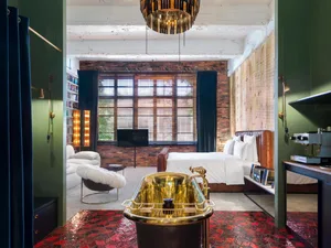 Modern industrial bedroom with brick walls, wood accents, and a polished marble bathtub.