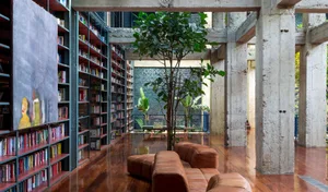 A modern, industrial-style library with concrete pillars and shelves filled with books.