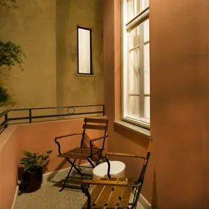 A modern balcony featuring a wooden chair and a white object, illuminated by natural light through a window
