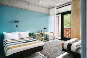 Modern bedroom featuring concrete walls, wooden furniture, and striped bedding.