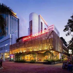 A modern storefront with large windows and tall columns illuminated by bright orange lights at dusk.