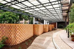 A modern garden with brick walls and wooden pathways under a glass ceiling.