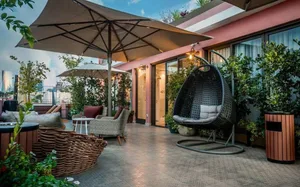 A modern, concrete-themed interior design space featuring a lounge seating area, hanging egg chair, and plant decor.