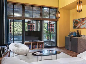 A modern living room with a glass coffee table, white couch, and wooden paneling on the walls and ceiling.