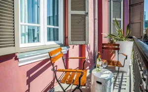 A modern residential balcony featuring wooden furniture, including a table, chairs, and a potted plant.