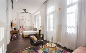A modern residential interior design featuring a bedroom with wood furniture, cotton textiles, and a colorful rug.
