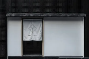 A storefront with a white banner featuring a geometric pattern and the text 'Zen Tokyo'. The storefront has a white wall and 
