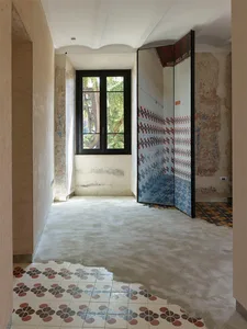 Concrete bathroom renovation with patterned tile floor and mosaic tile wall, featuring a modern shower enclosure.
