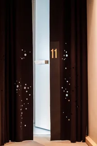 A black curtain with perforations and the number 11 displayed on it, indicating the room number of a hotel.
