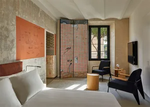 A bedroom with industrial design features, including vintage concrete walls and floors with a red and white pattern, and blac