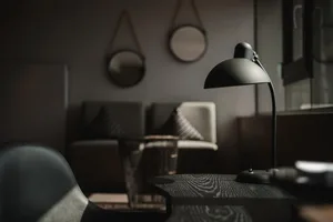 A minimalist workspace featuring an industrial-style desk with a black metal lamp and leather chair.