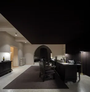 An office space with a minimalist design, featuring black furniture on a carpeted floor.
