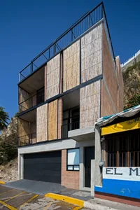 A modern residential building with a combination of concrete and wooden panels.