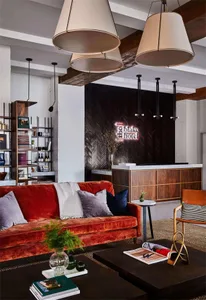 A modern industrial lobby featuring brick walls, a wooden reception desk, and a comfortable seating area with a red velvet so