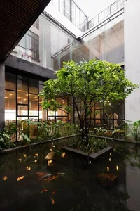 Modern living room featuring greenery, glass, concrete and water elements.