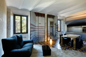 A modern living room featuring a blue sofa, a coffee table, and a marble table with black chairs.