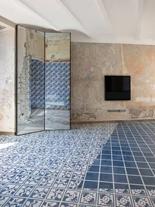 A modern living room with a tiled floor and concrete walls