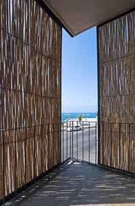 Modern balcony with bamboo railings overlooking the ocean.