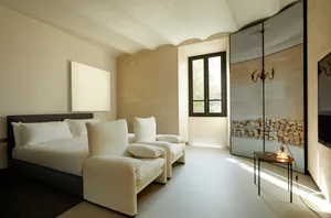 A minimalist modern residential interior featuring white fabric furnishings and textured plaster walls.