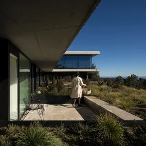 A modern residential exterior made of concrete, featuring clean lines and large glass windows.