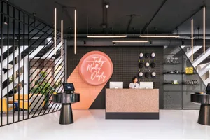 A modern lobby featuring concrete walls and floors, with a reception desk and neon sign