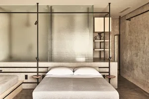 A modern minimalist bedroom with a concrete and metal headboard.