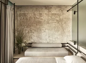 Modern minimalist bedroom with concrete and wood elements, featuring a bed with a concrete headboard and wooden headboard.