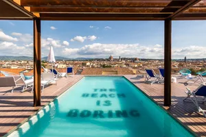 A rooftop pool with a view of a cityscape in Tuscany.
