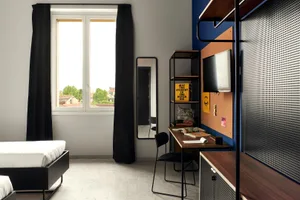 Contemporary bedroom interior with metal frame bed, wooden desk, and fabric chair.