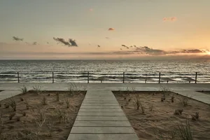 A scenic beach view with a wooden pathway leading towards the ocean.