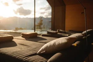 Modern relaxation room with wooden furniture and a scenic view of mountains and sunset.