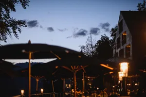 Nighttime scene of a modern restaurant with metallic decorations and illuminated patio lanterns.