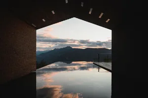A modern architecture view of a pool with glass walls, metal accents, and reflective water.