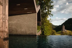 Modern wooden building with concrete facade in a Swiss Alps setting.