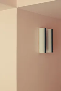 Modern metallic sconces mounted on a pink retail interior wall, highlighting clean lines and minimalist design.