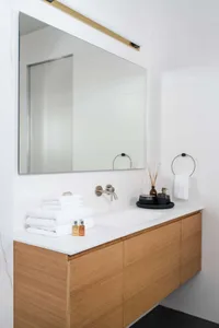 Modern bathroom with wooden vanity, marble countertop, and white towels
