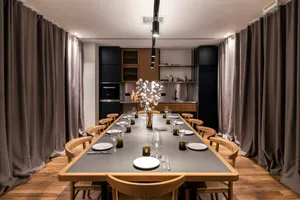 Modern dining room with wooden chairs, glass vase centerpiece, and gray table setting.