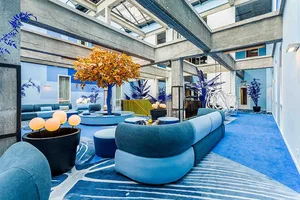 Lobby area with a modern blue sofa, concrete columns, and potted plants