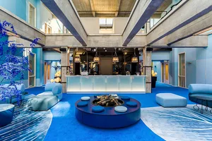 Modern lobby featuring a concrete ceiling, hanging lights, and blue seating