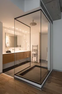 Modern minimalist bathroom with glass shower enclosure and marble accents.