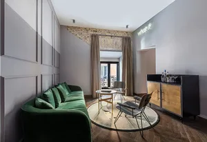 Modern industrial living room with green velvet sofa, round coffee table, and metallic chairs.
