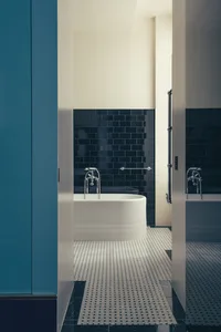 Modern bathroom with black subway tiles on the walls, white bathtub, and black and white tile flooring.