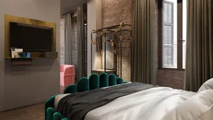 A modern bedroom featuring an emerald green upholstered headboard against a brick accent wall, with a TV stand and a pink arm