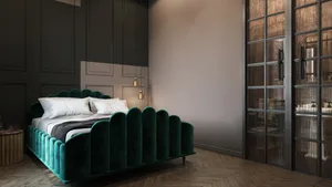 A modern bedroom featuring a striking green velvet headboard and white bedding on a wooden floor and dark walls.