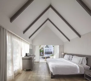 A modern bedroom featuring a white bed with a wooden frame, large windows with sheer curtains, and a wooden floor.