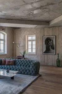 Modern living room interior with concrete walls, grey sofa, and minimalistic decor.
