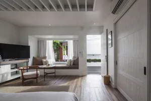 Modern hotel suite featuring white wood, a seating area, and a view of the ocean.