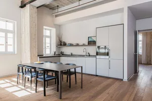 Modern kitchen interior with light wood flooring, white cabinets, and stainless steel appliances.