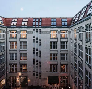 Modern residential apartment building with a brick-patterned facade and lit windows.